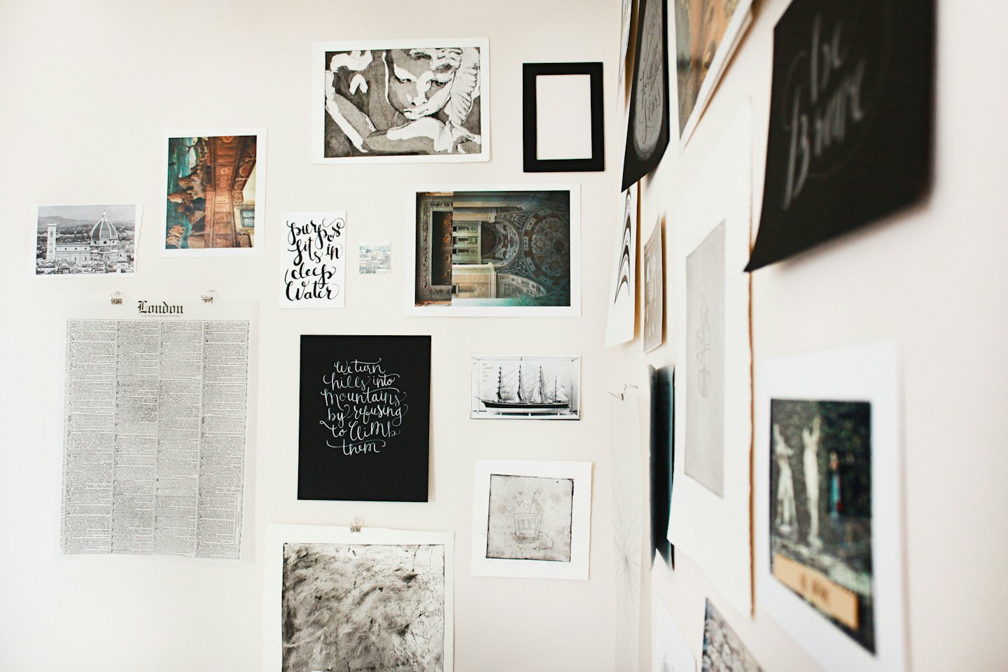 Ungerahmte Drucke und Fotos an einer hellen Wand.